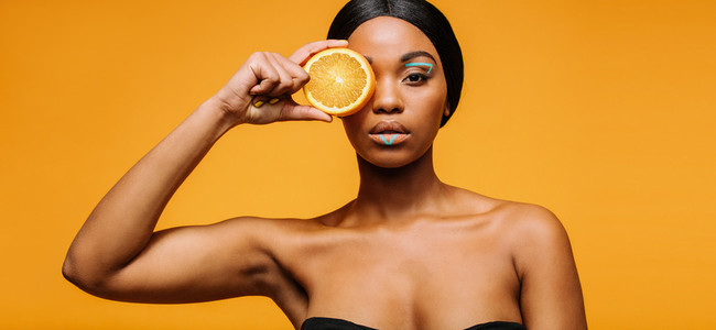 Woman with artistic make up holding an orange