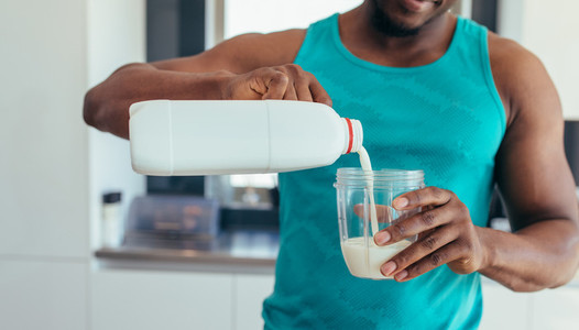 Man pouring milk in glass for breakfast