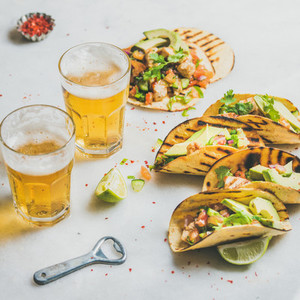 Healthy corn tortillas with beer in glasses over light background