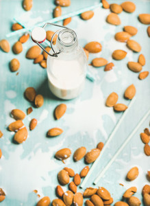 Dairy alternative almond milk in bottle over blue background