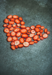 Heart shaped pieces of strawberries over grey background copy space