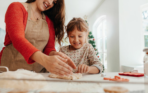 Mother teaching daughter to make cookies for Christmas