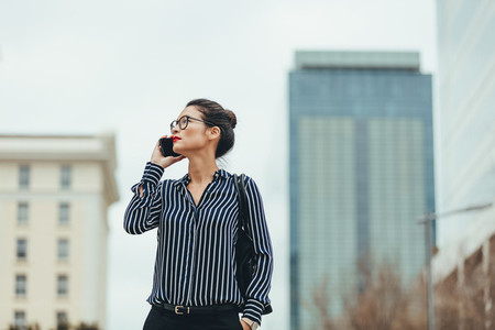 Businesswoman walking outdoors with cellphone