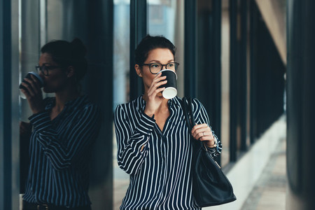 Businesswoman outside office building drinking coffee