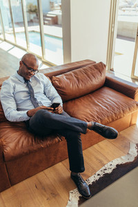 Businessman sitting on lounge using mobile phone