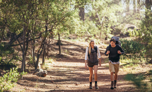 Hiking couple walking in forest wearing backpacks