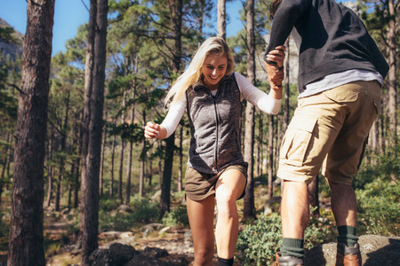Hiking couple walking on rocks in forest wearing backpacks