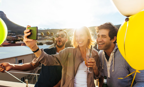 Group of friends taking selfie at rooftop party