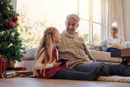 Senior man and granddaughter with digital tablet at home