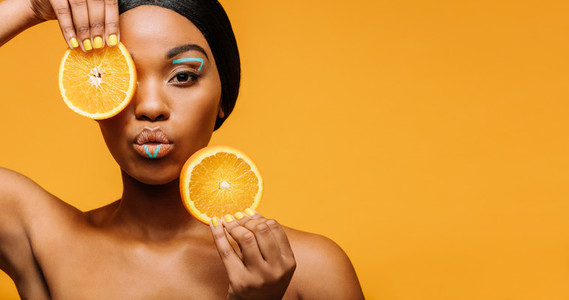 Woman with artistic makeup and orange in hand