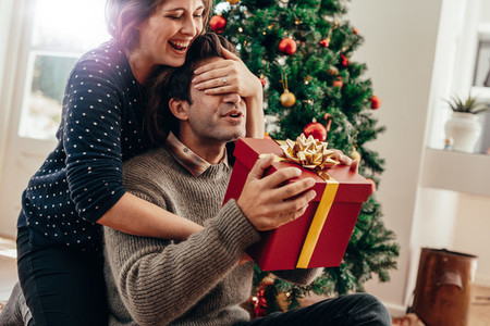 Young couple having fun celebrating Christmas with gifts