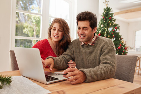 Happy young couple shopping online for christmas