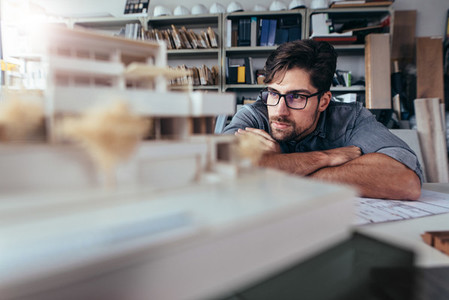 Architect in office looking at house model