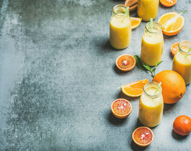 Healthy yellow smoothie in bottles over concrete background copy space