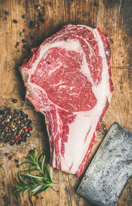 Raw beef steak rib eye with seasoning and knife wooden background