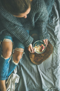 Woman in sweater and jeans eating rice coconut porridge