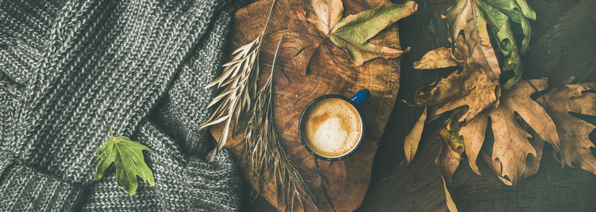 Autumn coffee concept with leaves and grey sweater wide composition