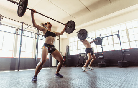 Man and woman doing weightlifting exercises in gym