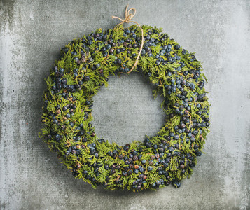 Christmas decorative wreath with bilberries over grey concrete wall background