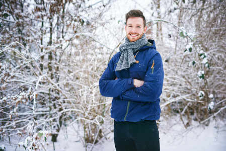 Young man smiling on snowy forest background