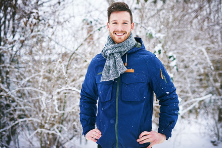 Cheerful male in coat on winter background