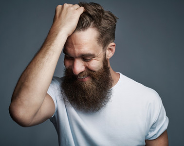 Laughing bearded man holding hair and laughing