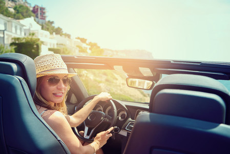 Young woman in convertible car looking back
