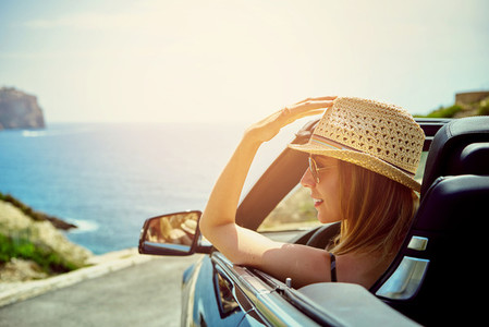 Side view on smiling woman in convertible car