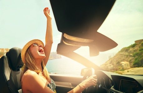 Excited woman driving her car with raised fist
