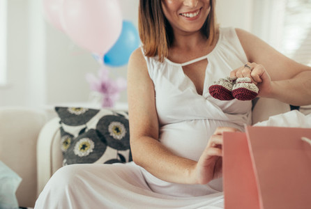 Pregnant woman holding small booties for unborn baby