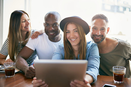 Group of smiling people sitting with tablet