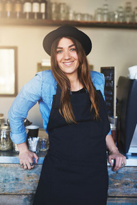 Happy barista leaning against counter in cafe