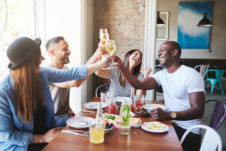 Happy adults toasting with drinks in restaurant