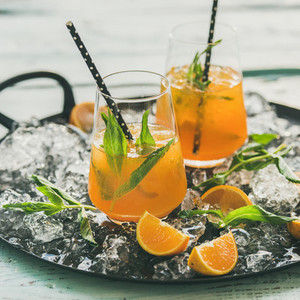 Refreshing cold alcoholic summer cocktail with orange and peppermint