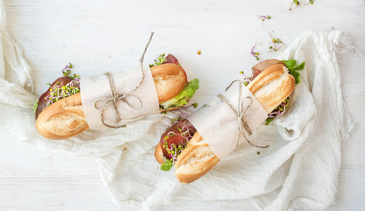 Sandwiches with beef fresh vegetables and herbs over white wood backdrop
