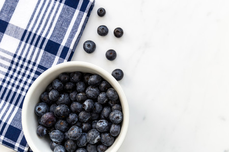 Bowl of blueberries fruit on white marble background