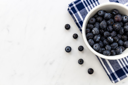 Bowl of fresh blueberries on white marble background