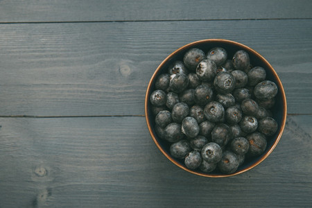 Bowl of blueberries on wood table with copy space