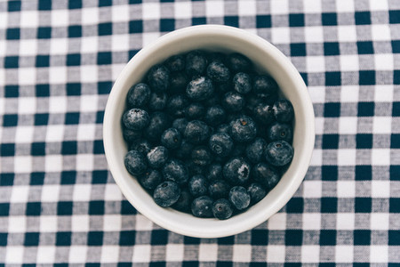 Bowl of blueberries overhead on tablecloth