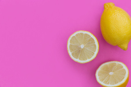 Sliced lemons on bright pink background with copy space