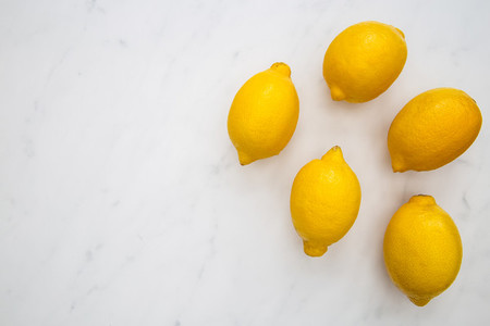 Bunch of lemons on white marble background with copy space