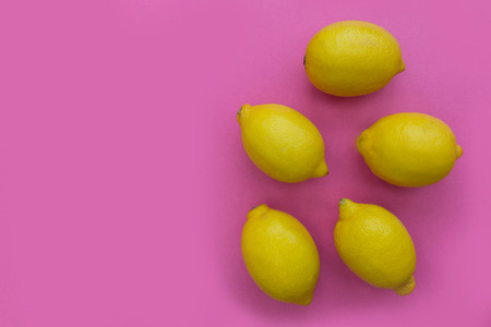 Bunch of lemons on bright pink background