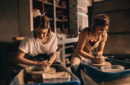 Two women at a pottery workshop making clay pots