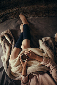 Woman lying on bed with a cup of coffee