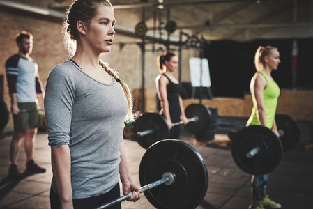 Woman in class doing dead lift barbell exercise
