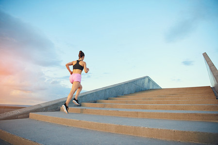 Fit healthy young woman jogging up stairs