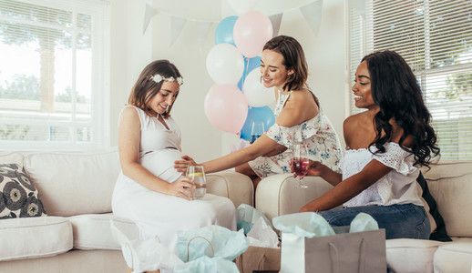 Female touching tummy of pregnant woman at baby shower