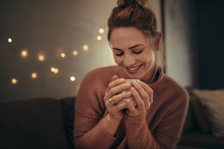 Smiling woman drinking coffee in winter at home