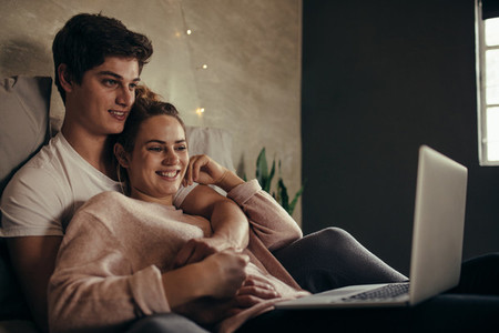 Hygge couple with laptop on bed