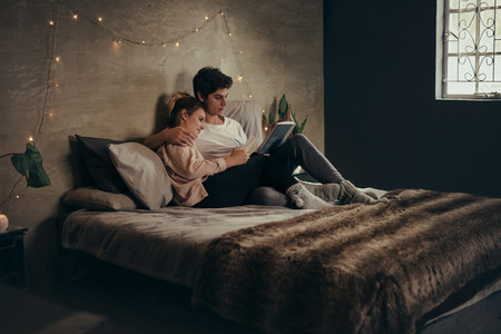 Couple relaxing on bed and reading books